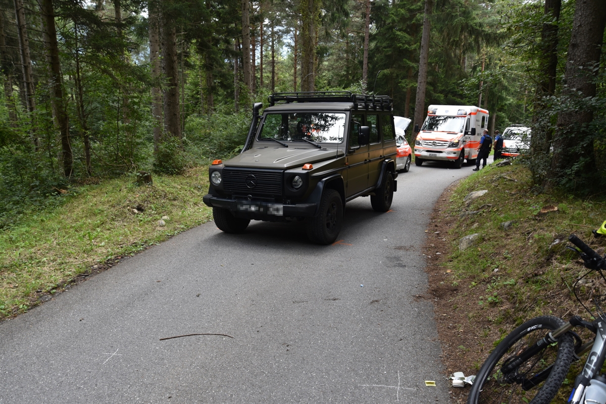 Militärfahrzeug in Strassenmitte, Fahrrad im Vordergrund am rechten Strassenrand.