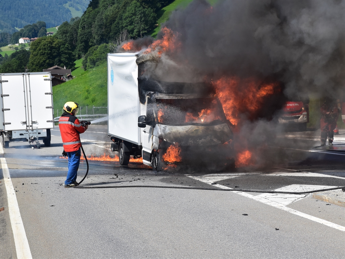 Der in Vollbrand stehende Lieferwagen wird von einem Feuerwehrmann gelöscht.