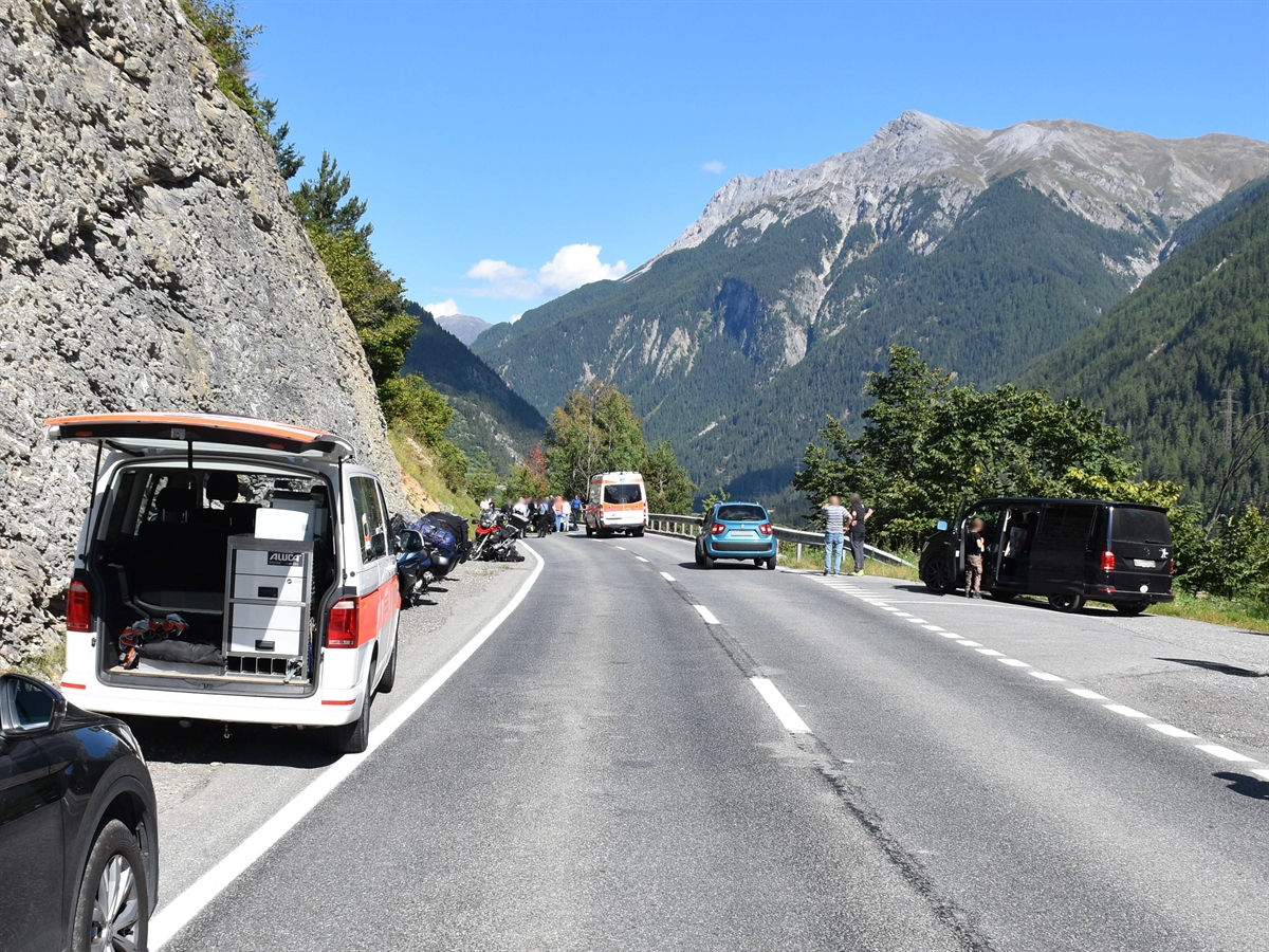 Die H27, rechts die Abzweigung nach Sur En. Links am Strassenrand Motorräder und ein Polizeiauto. In Bildmitte ein Ambulanzfahrzeug und Personen auf der Fahrbahn.
