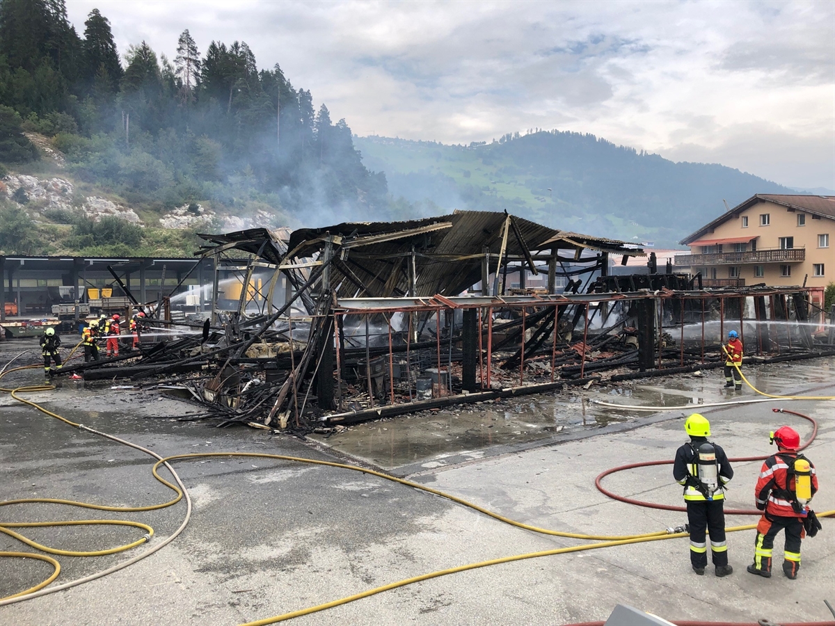 Die gelöschte Lagerhalle, aus welcher noch Rauch aufsteigt. Feuerwehrleute im Einsatz.