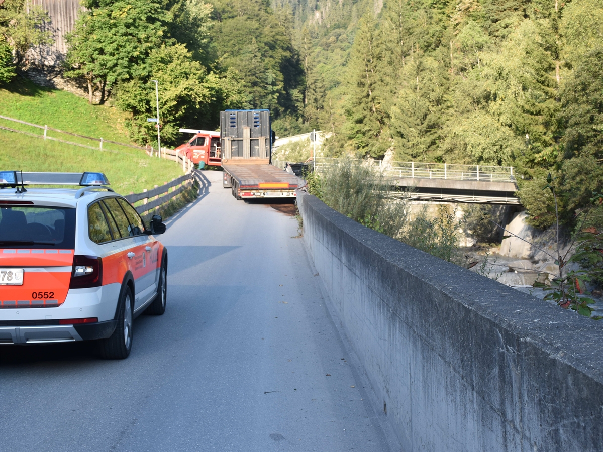 Die ansteigende Strasse, links ein Polizeiauto, rechts eine Mauer, die den Furner Bach abgrenzt weiter oben das Sattelmotorfahrzeug und ein Feuerwehrauto.