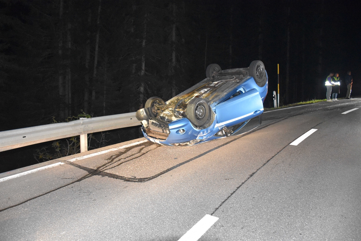 Personenwagen liegt auf dem Dach am Fahrbahnrand