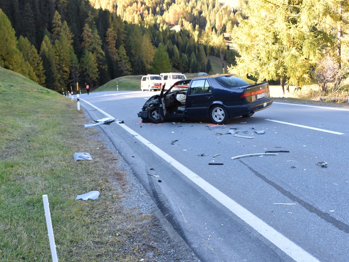 Ein frontal stark beschädigtes schwarzes Auto – umsäumt von Autoteilen – mitten auf der Strasse.
