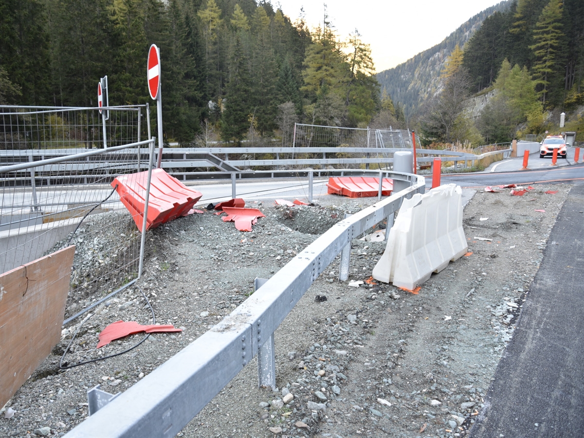 Ein Baustellenbereich, in welchem rote und weisse beschädigte Verkehrsführungselemente (sogenannte New Jersey Elemente) rumliegen. Weitere Schäden an der Strasseninfrastruktur.