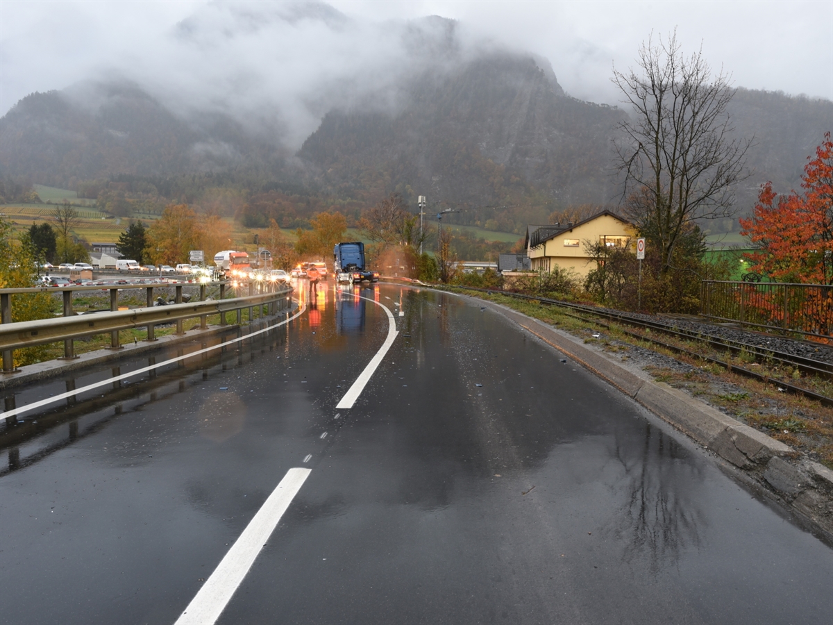 Linkskurve der Untervazerstrasse in Richtung Anschluss N13 gesehen. Im Hintergrund ein Polizist der den Verkehr in Richtung Untervaz anhält sowie der verunfallte Sattelschlepper.