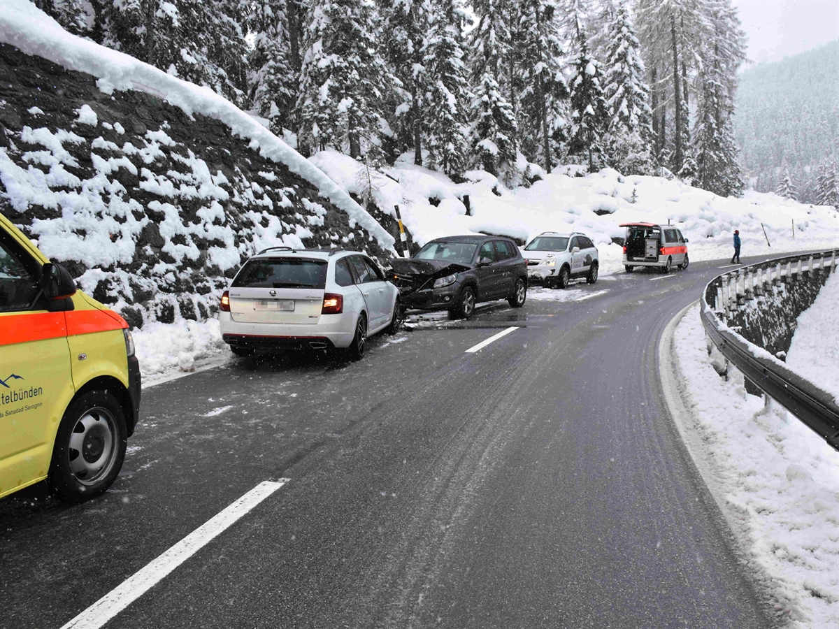 Die Unfallkurve von der rechten Spur aus fotografiert. Auf der linken Spur eine Ambulanz, die Unfallfahrzeuge, ein weiteres Fahrzeug und ein Polizeiauto. Die Strasse ist mit Schneematsch bedeckt. 