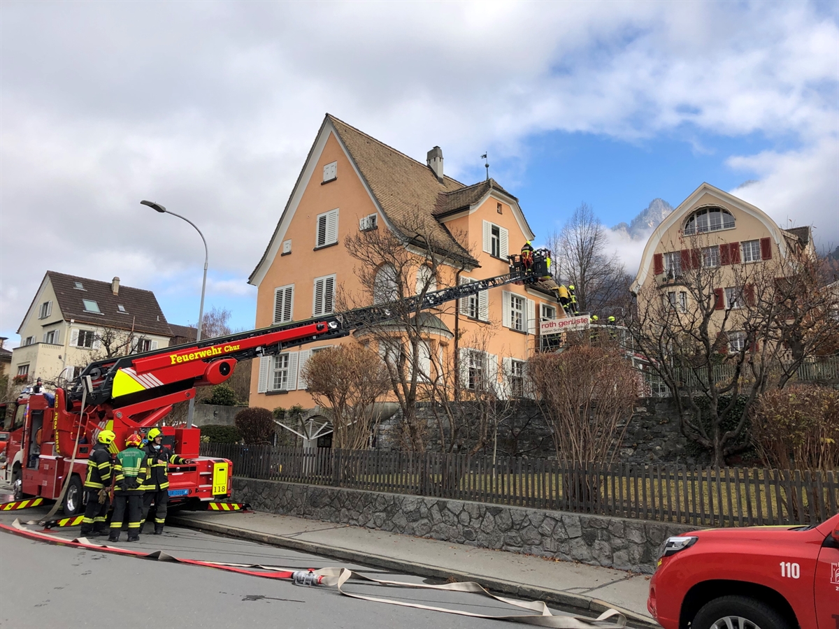 Hubretter der Feuerwehr Chur bringt Feuerwehrleute zur Hausfassade des Einfamilienhauses. Auf dem Balkon befinden sich weitere Einsatzkräfte der Feuerwehr
