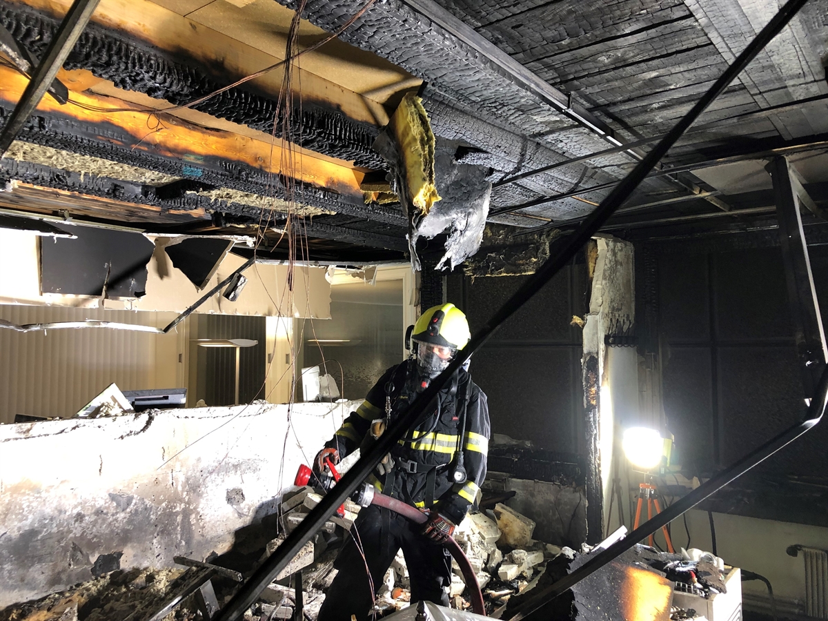Ein ausgebrannter Raum mit einem im Einsatz stehenden Feuerwehrmann. 