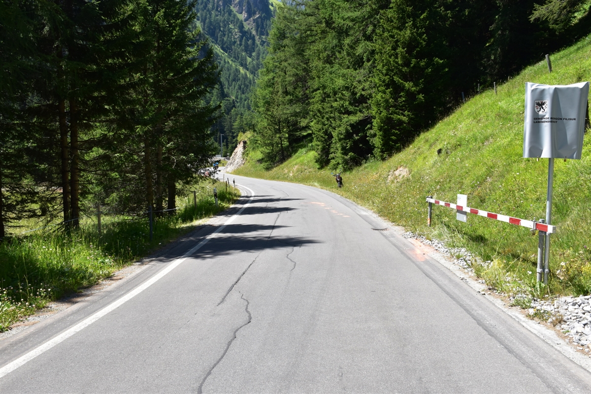 Albulastrasse in Preda Blick Richtung Bergün: Spuren am rechten Fahrbahnrand. Verunfalltes Motorrad ist im Hintergrund zu sehen.