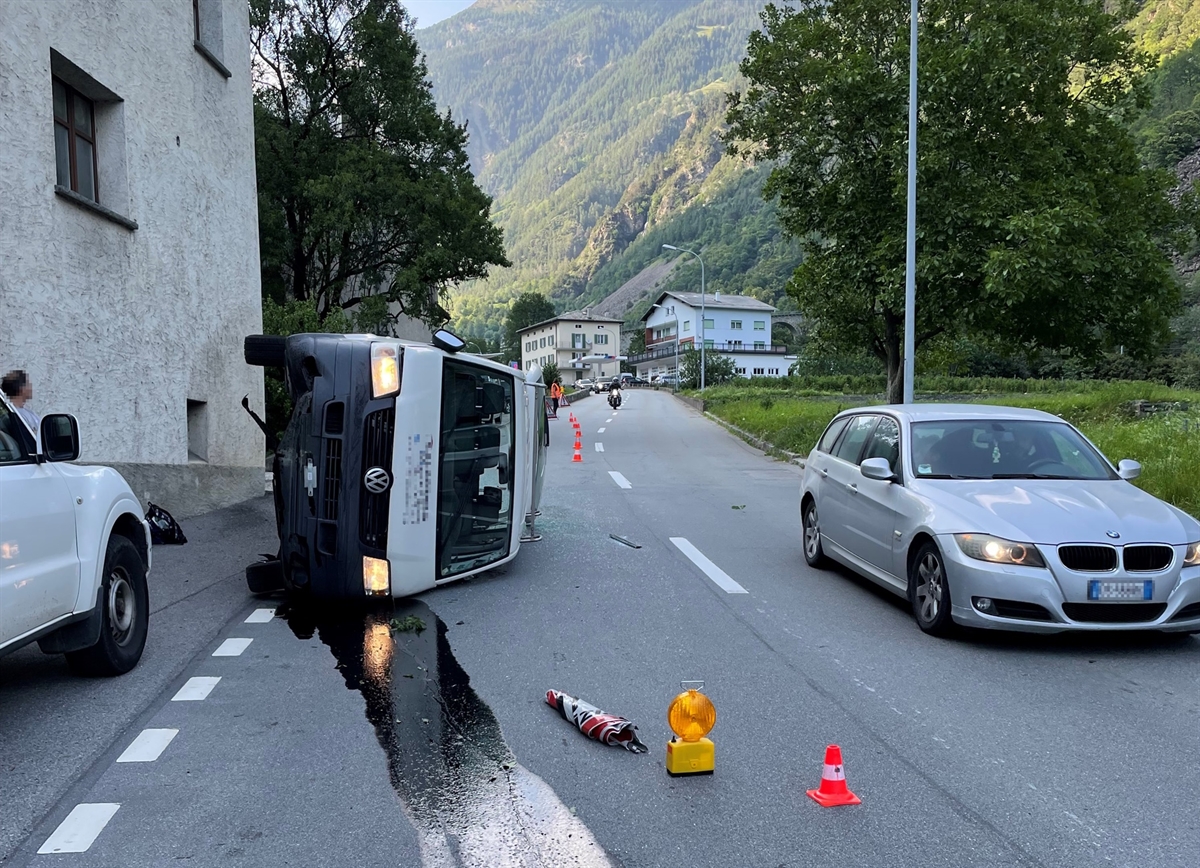 Lieferwagen liegt auf der linken Fahrzeugseite auf der Fahrbahnhälfte Richtung Campascio. Der Verkehr wird an der Unfallstelle vorbeigeführt.
