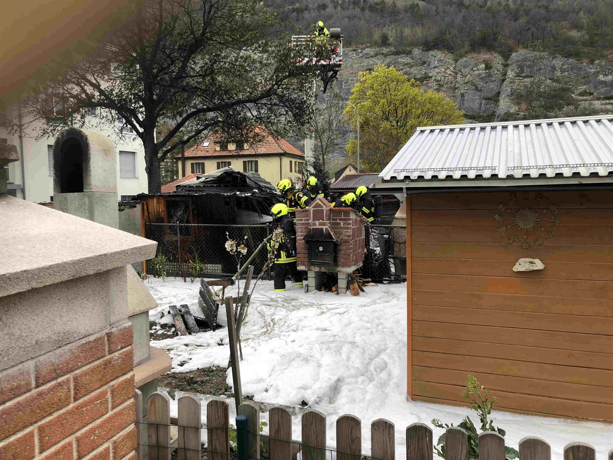 Die Feuerwehrleute am Arbeiten zwischen den Gartenhäusern in der Schrebergartenanlage.