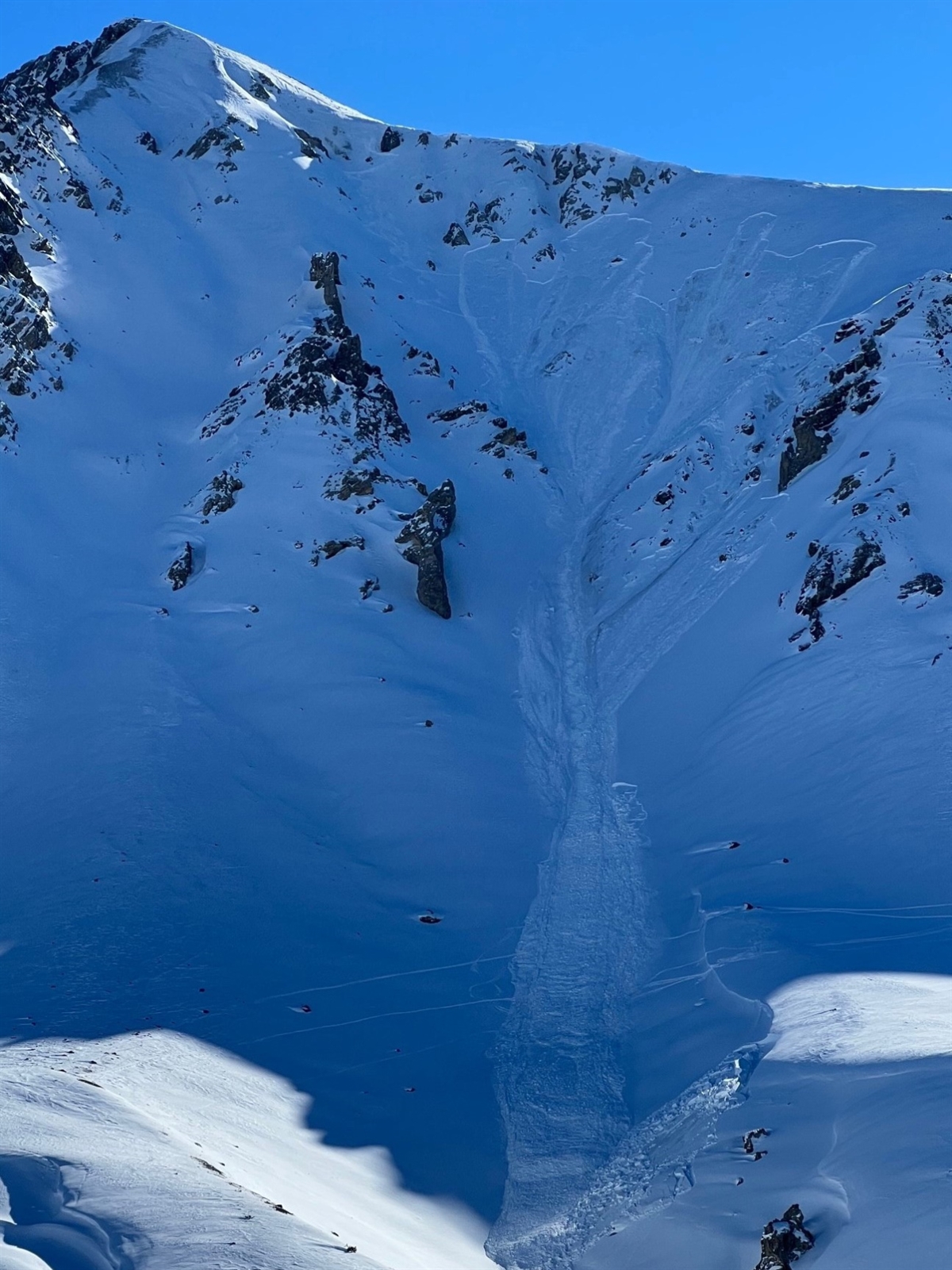 Schneebedeckter Piz Daint, Bergflanke mit Abrissstelle des Schneebretts und Lawine im Couloir.