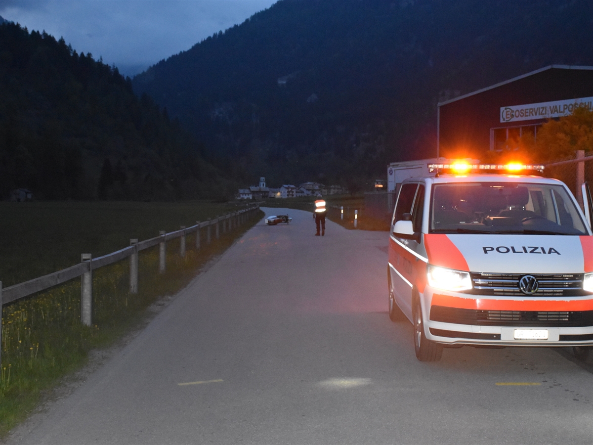 Im Hintergrund liegt der Roller auf der Nebenstrasse. Ein Polizist steht daneben. Im Vordergrund ein Polizeifahrzeug mit eingeschalteter Warnblinkanlage
