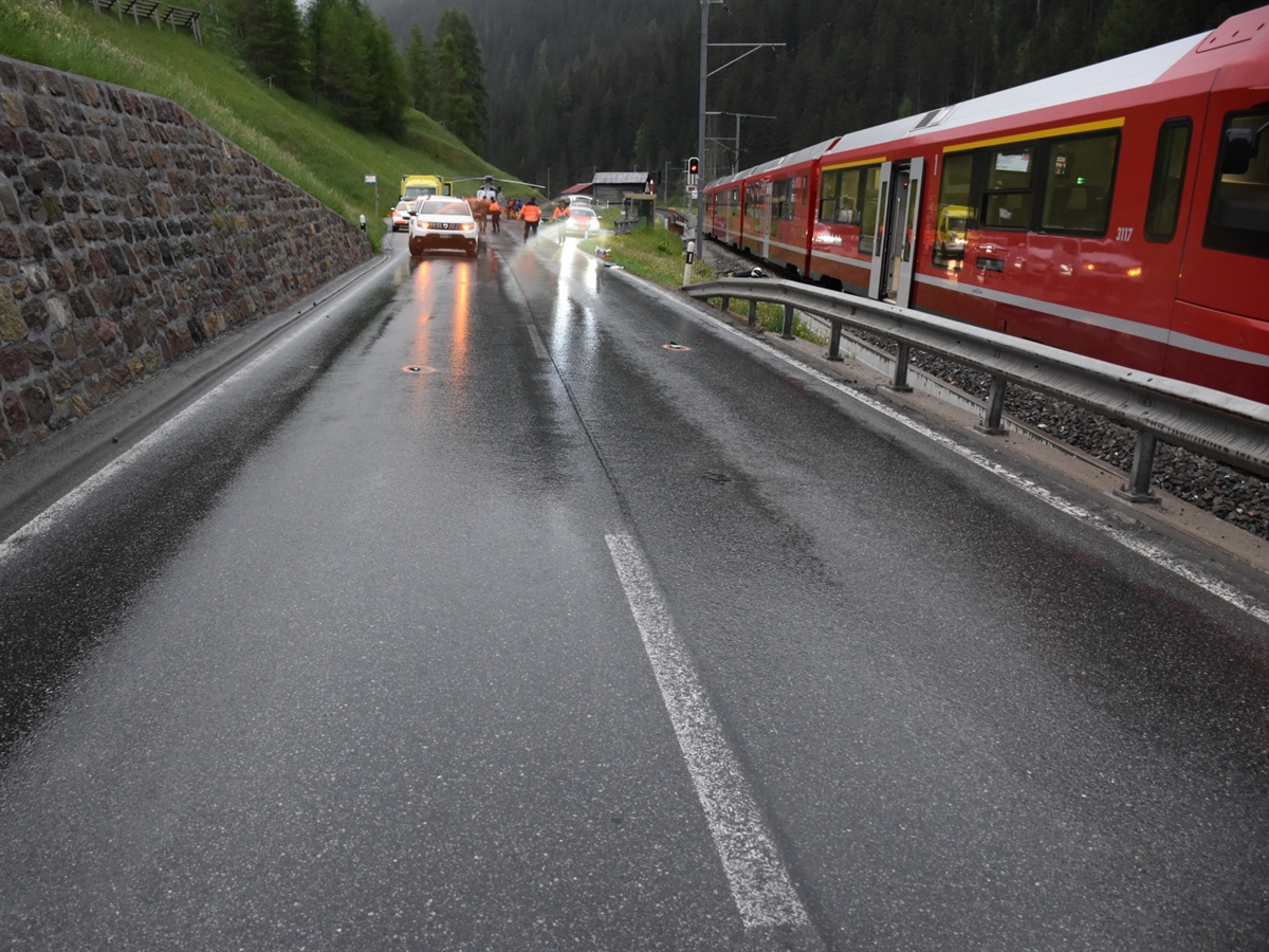 Unfallstelle mit Zugskomposition auf der rechten Seite. Im Hintergrund Ambulanzfahrzeug, Armee-Helikopter sowie Polizeifahrzeuge