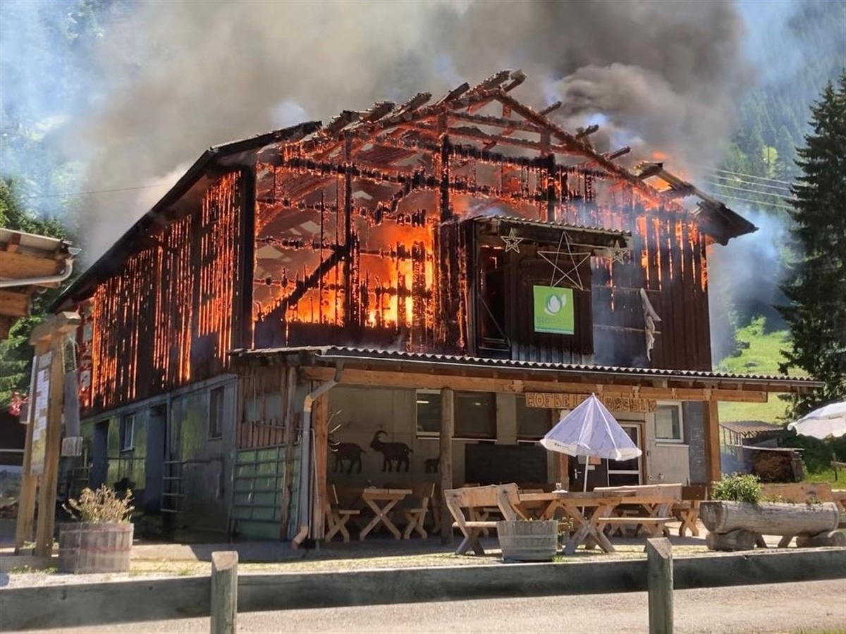 Der in Vollbrand stehende Stall, umgeben von weiteren landwirtschaftlichen Gebäuden.