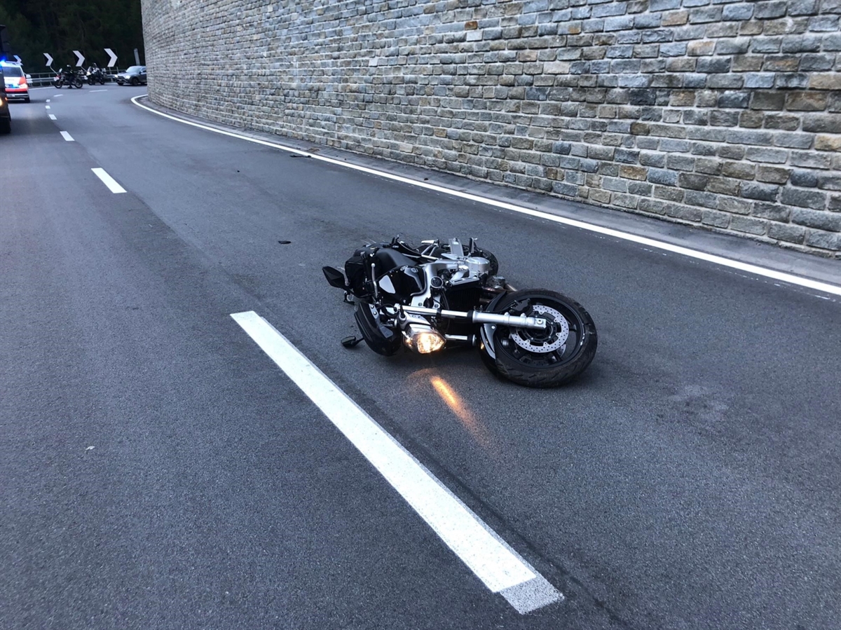 Das Motorrad liegt auf der rechten Fahrzeugseite in der Mitte der Hauptstrasse. Im Hintergrund die Linkskurve sowie ein Patrouillenfahrzeug der Kapo GR