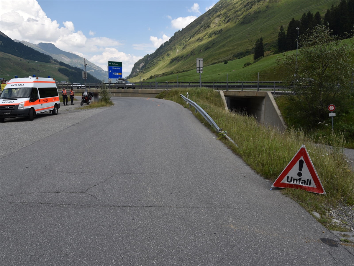 Unfallstelle mit der Linkskurve im Hintergrund. Vorne rechts steht ein Faltsignal mit Unfall und rechts steht ein Patrouillenfahrzeug der Polizei. Hinter diesem stehen zwei Polizisten neben dem Unfallmotorrad.
