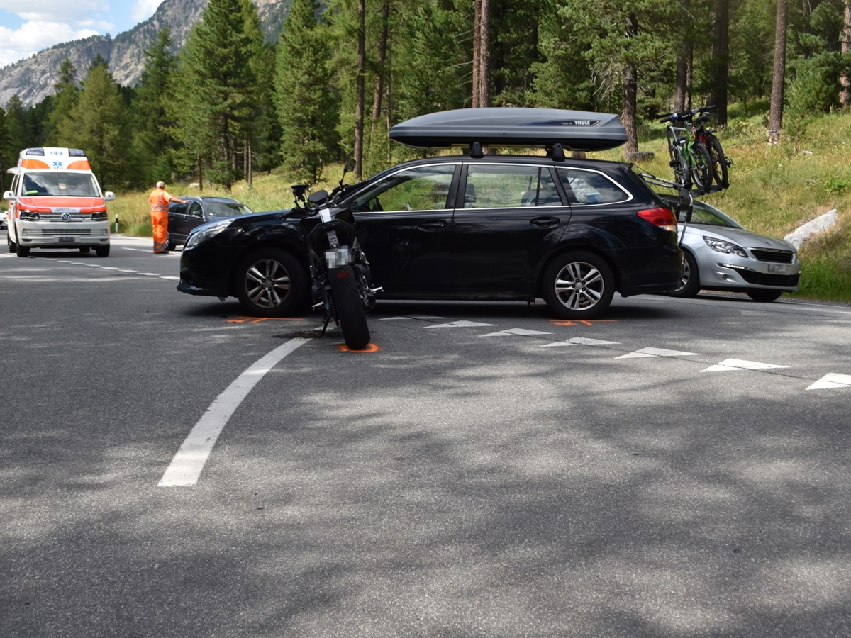 Verzweigung Morteratsch. In Bildmitte das abbiegende Auto und davor das Motorrad auf dem Seitenständer. Im Hintergrund ein Ambulanzfahrzeug sowie ein Mitarbeiter des Tiefbauamtes Graubünden, welcher den Verkehr regelt.