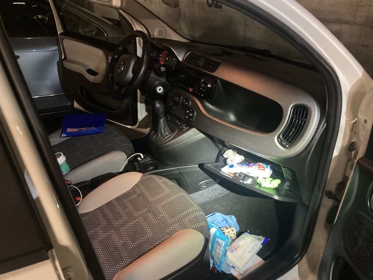Blick durch die vordere rechte Türe in den Frontraum eines Autos, in welchem Unordnung herrscht.