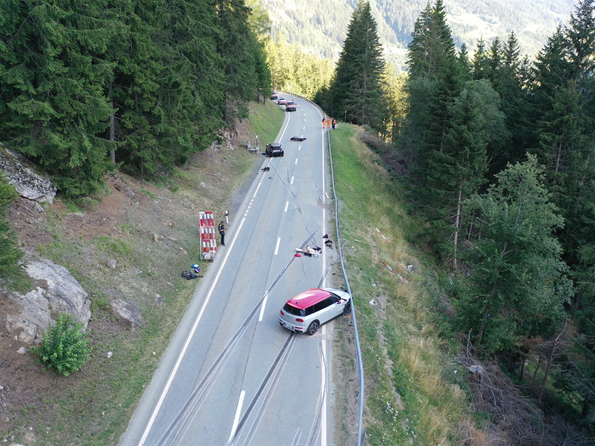 Luftaufnahme des Unfallabschnitts. Reifenspuren auf der Strasse und rechts ein beschädigtes Auto an der Leitplanke. Weiter entfernt das zweite, ebenfalls beschädigte Auto. Nahe diesem das auf der Strasse liegende Motorrad. Im Hintergrund Einsatzkräfte.