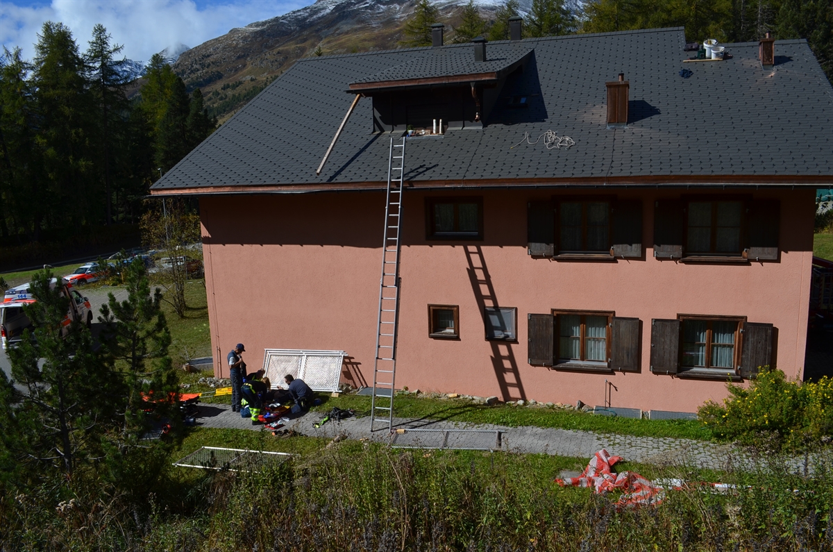 Leiter lehnt an zweistöckigem Haus, Rettung kümmert sich um Verletzten