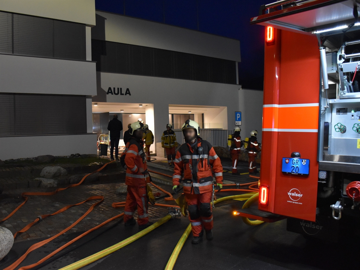 Einsatzfahrzeug der Feuerwehr. Am Boden sind mehrere Wasserschläuche. Eine Vielzahl an Einsatzkräfte sind im Löscheinsatz.
