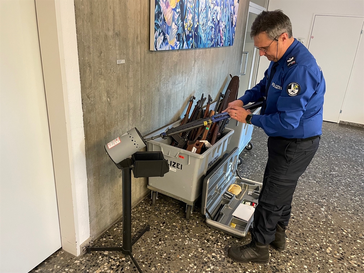 Der Polizist kontrolliert ob die Waffe entladen ist.