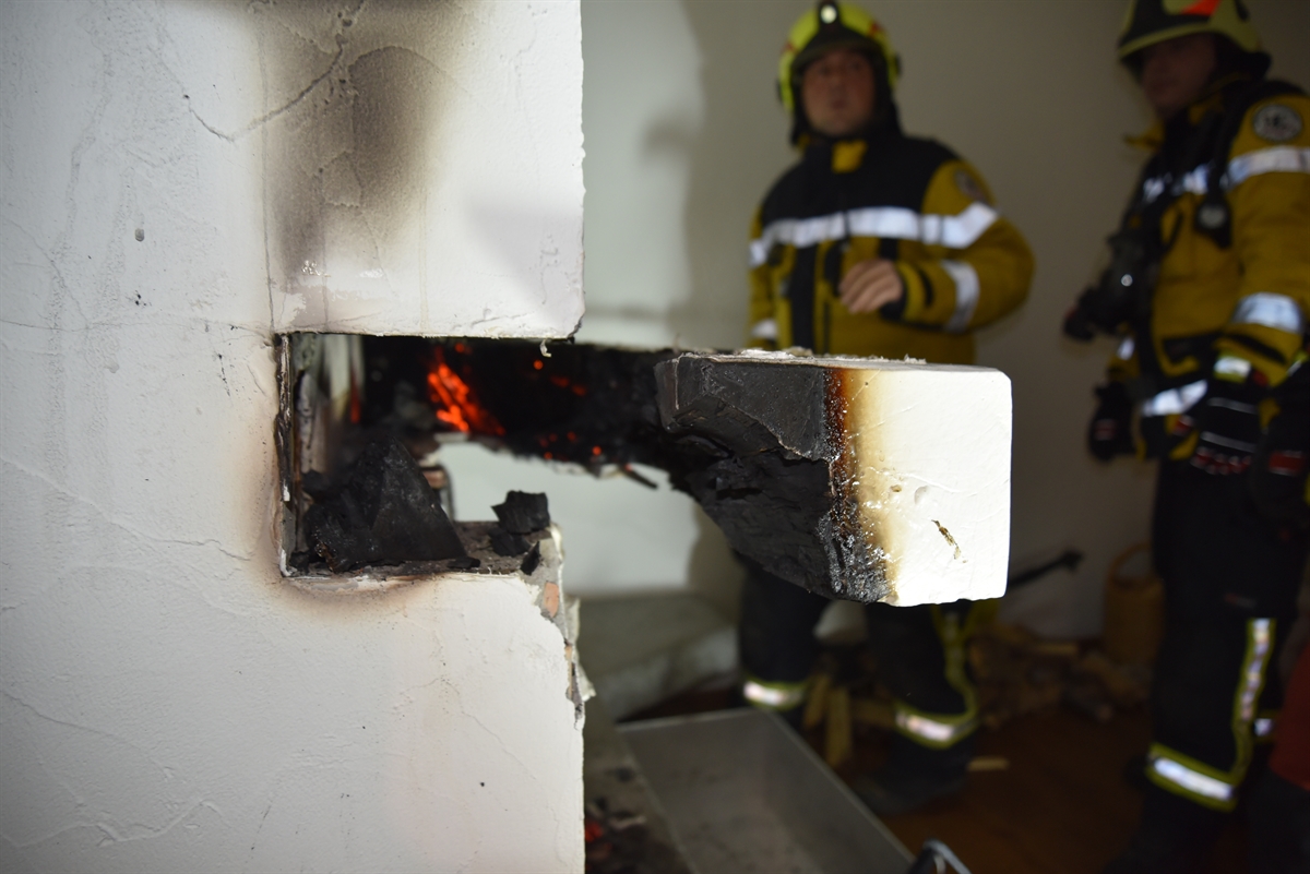 Glühender Holzbalken, zwei Feuerwehrleute