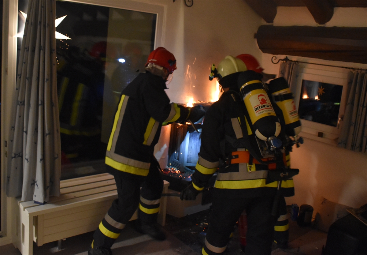 Drei Feuerwehrleute schlagen mit Werkzeug Holzbalken heraus