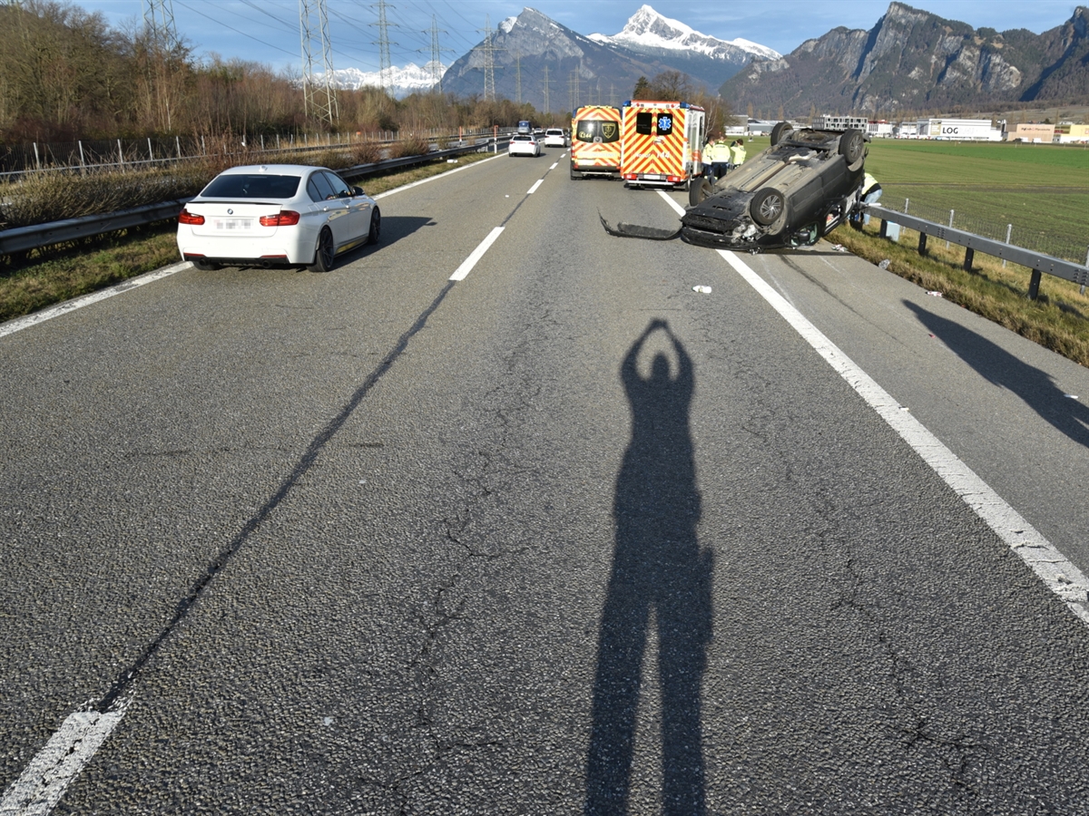 Nordspur der A13 mit dem auf dem Dach liegenden Auto. Im Hintergrund zwei Ambulanzfahrzeug mit drei Sanitäter daneben. Der Fahrzeugverkehr wird einspurig am Unfallort vorbeigeführt.