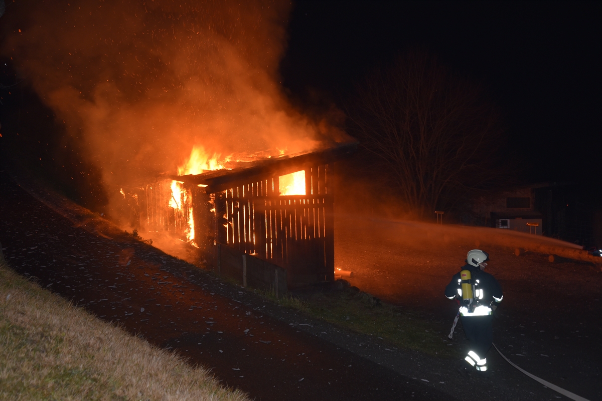 Flammen und Rauch über Holzschopf in der Nacht