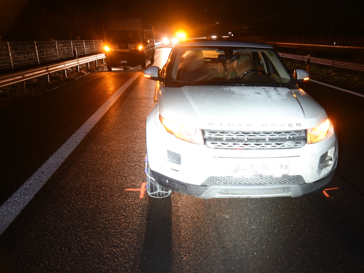 Nachtaufnahme. Das weisse Unfallauto von vorne auf der Normalspur. Links dahinter der Lieferwagen auf dem Pannenstreifen. Im Hintergrund weitere Fahrzeuge.