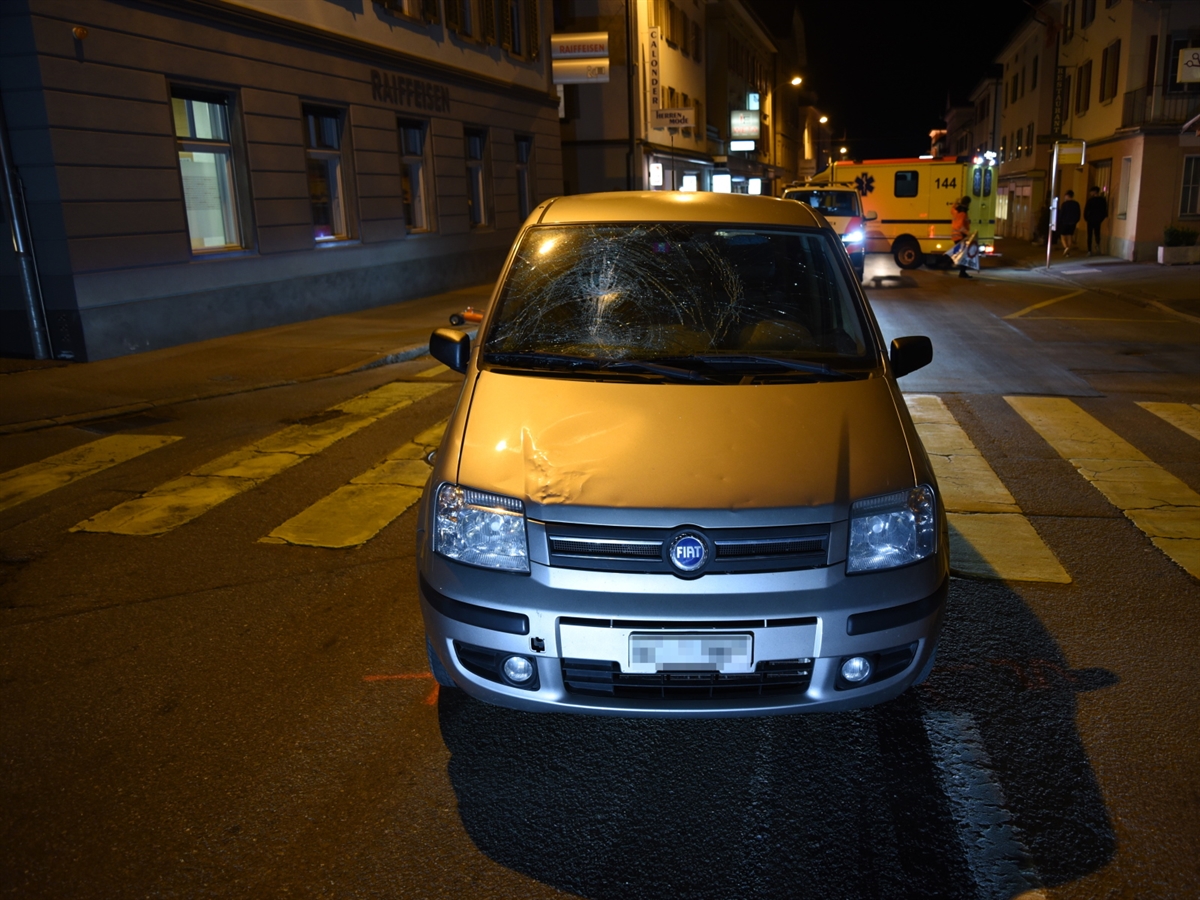Das Unfallauto von vorne mit eingedrückter Frontscheibe. Der Heckbereich des Autos steht auf dem Fussgängerstreifen, weiter entfernt ein Polizei- und ein Ambulanzfahrzeug. 