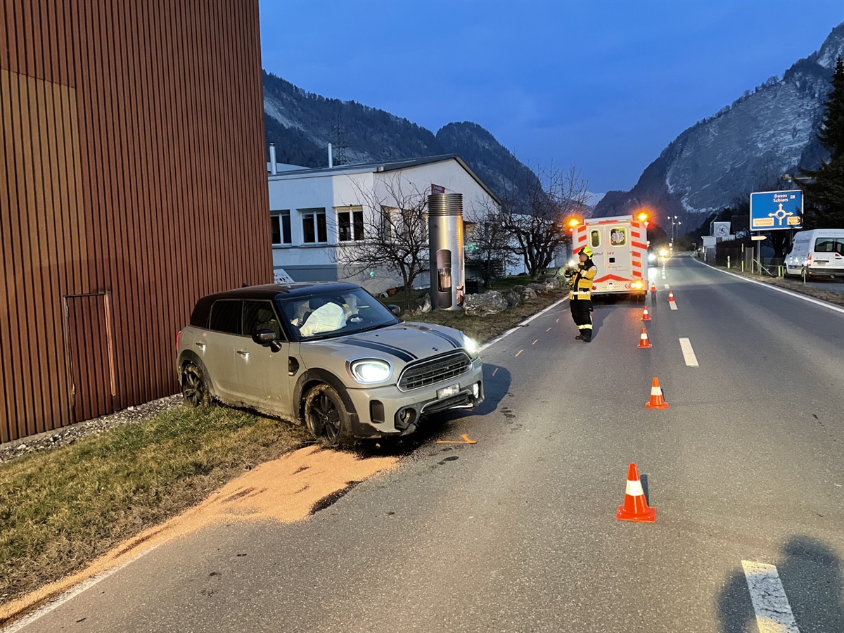 Unfallauto links neben der Fahrbahn mit Front in Richtung Strasse. Im Hintergrund ein Rettungswagen.