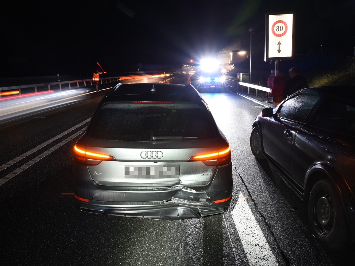 Abendaufnahme. Links von hinten das beschädigte vordere Fahrzeug, rechts daneben das auffahrende Fahrzeug. Im Hintergrund ein Polizist, ein Polizeiauto und das Südportal des Isla Bellatunnels.