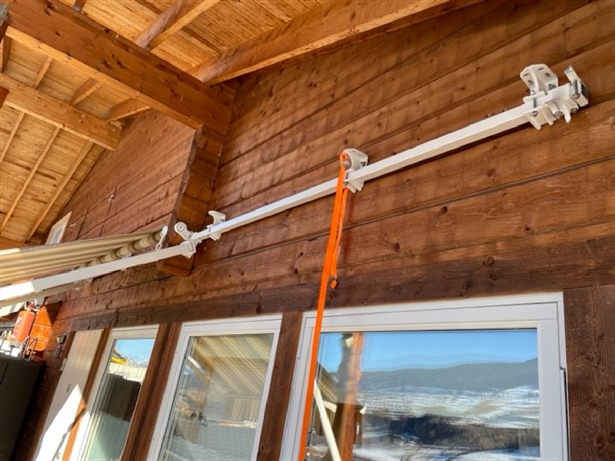 Die Aussenfassade eines Holzhauses. Oberhalb der Fenster links eine Sonnenstoren, rechts davon die Befestigungspunkte des weiteren Storens. 