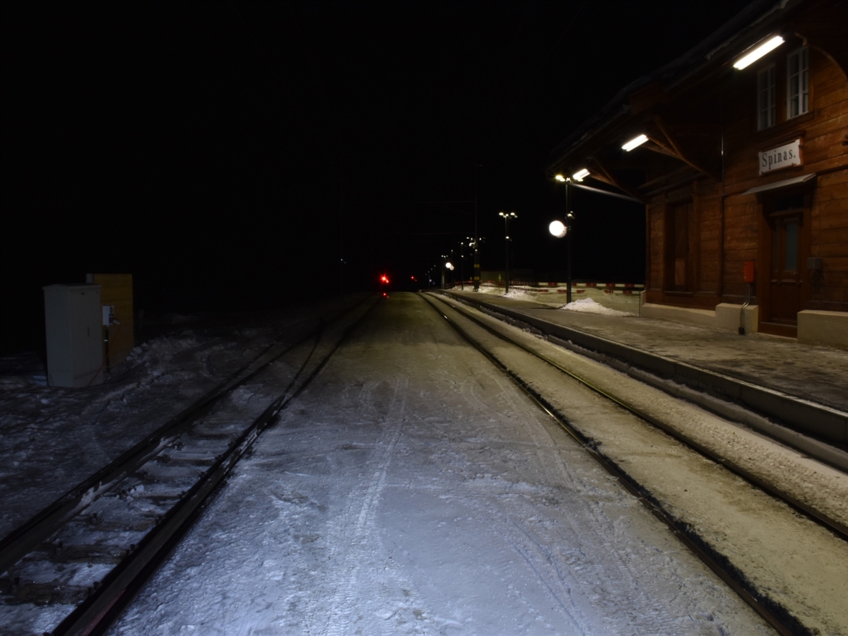 Zwei Geleisspuren beim Bahnhof Spinas. Zwischen diesen sind im Schnee Reifenspuren von einem Auto zu erkennen.
