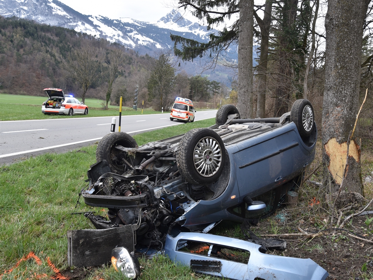 Das auf dem Dach liegende blaue Auto neben dem Baum. Im Hintergrund die Luzisteigstrasse sowie ein Rettungswagen und ein Patrouillenfahrzeug.