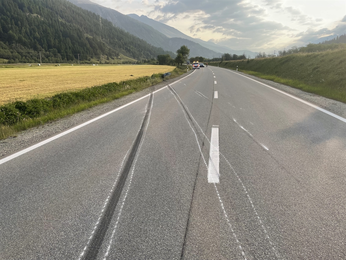 Schleuderspur auf der H27 über die Gegenfahrbahn in den Strassengraben. Im Hintergrund ein Patrouillenfahrzeug der Kantonspolizei Grabünden.