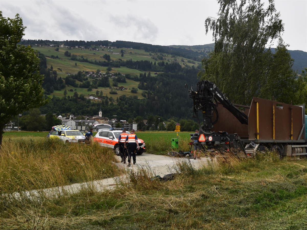 Die Verzweigung des Feldweges. Am rechten Bildrand steht der Motorkarren. Links im Bild zwei Polizisten und ein Polizeiauto. Hinter diesem der Einsatzwagen des Notarztes.