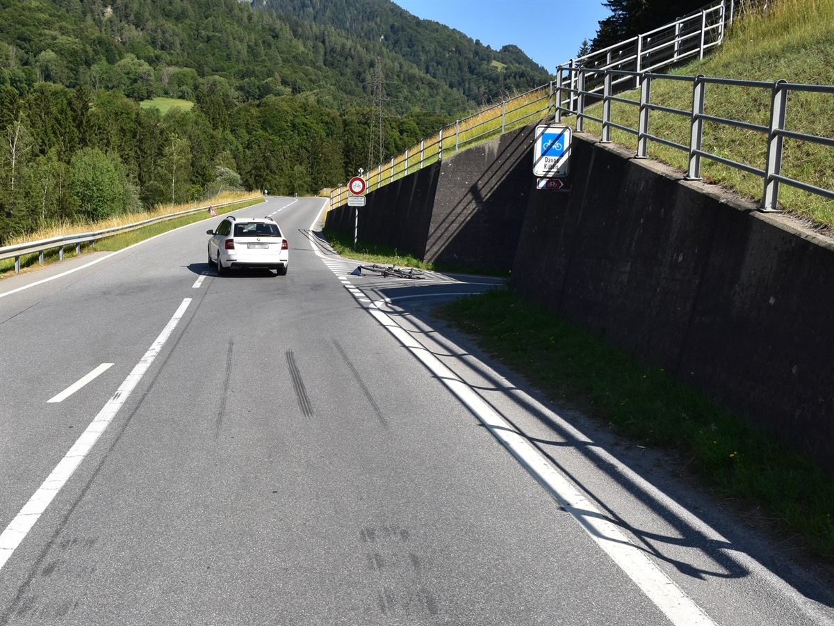 Geradeaus die Zubringerstrasse mit dem Auto. Rechts davon Verzweigung mit der Chlusstrasse auf welcher das E-Bike am Boden liegt. 