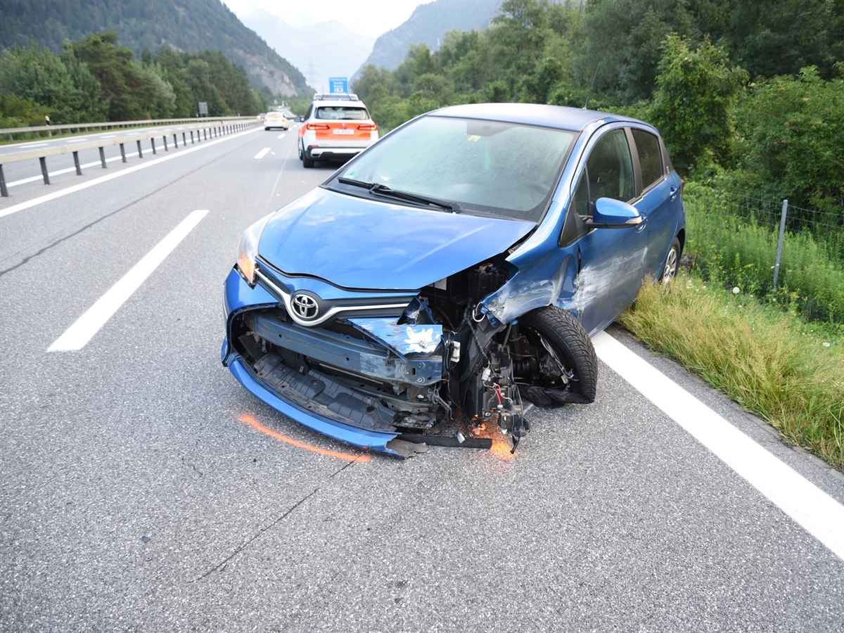 Das blaue Auto von schräg vorne. Die linke vordere Radaufhängung sowie die Fahrzeugseite sind stark beschädigt.