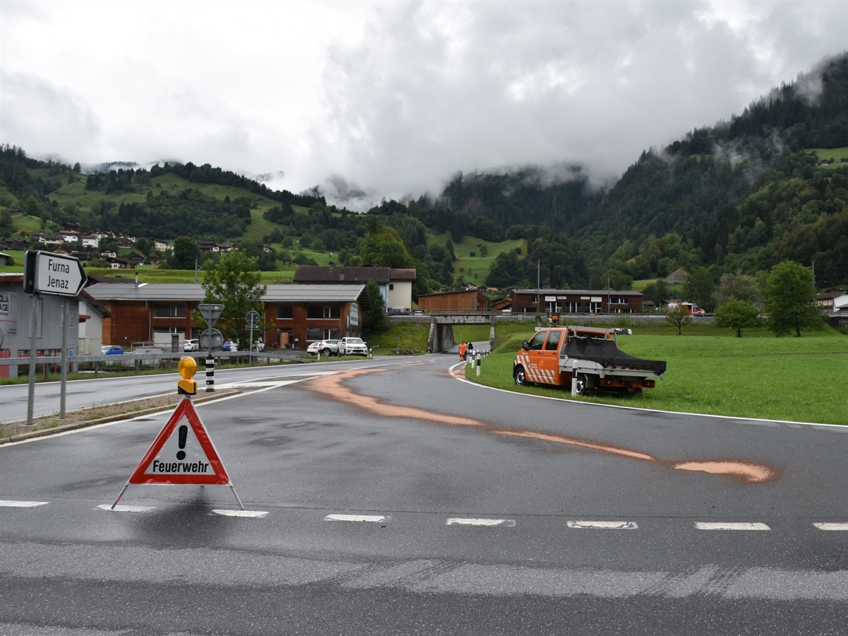 Der Anschluss Jenaz mit der Ölspur auf der Fahrbahn. Ein Fahrzeug des Tiefbauamtes sowie deren Mitarbeitenden sind neben der Fahrbahn. Mit einem Feuerwehr-Faltsignal wird die Ausfahrt gesperrt.