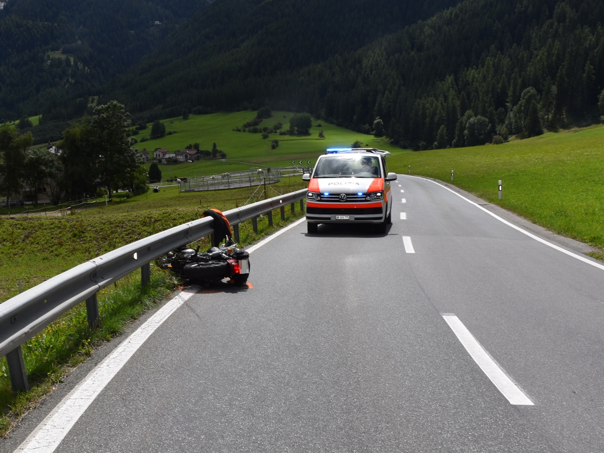 Das Motorrad liegt links im Bild unter der Leitplanke. Auf der Fahrbahn in der Bildmitte steht ein Polizeifahrzeug. Die Sicht ins Val Müstair rundet das sommerliche Bild ab.