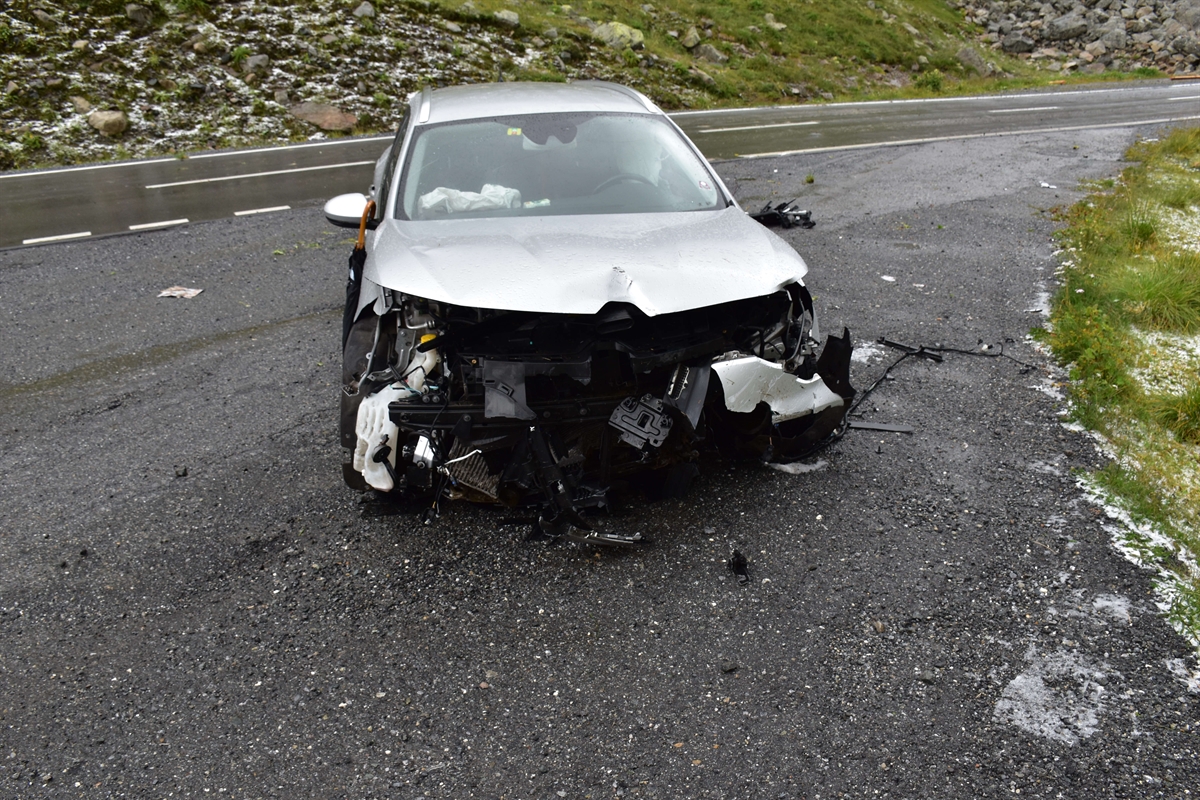 Im Vordergrund auf dem Kiesplatz der totalbeschädigte Personenwagen zu erkennen.