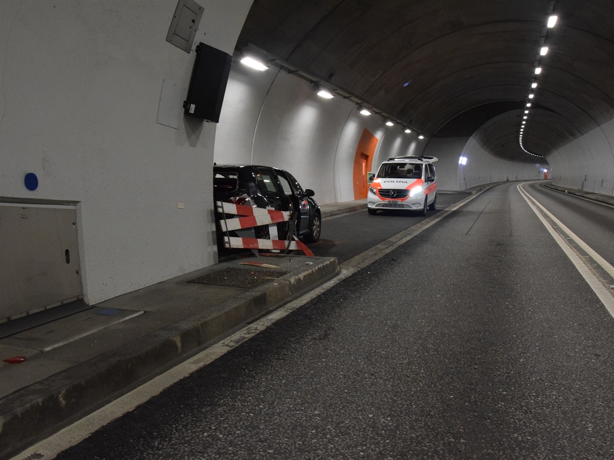 Das Unfallauto von schräg hinten in einer Notfallnische mit dem Heck an einer Wand. Ebenfalls in der Nische ein Polizeiauto von vorne.