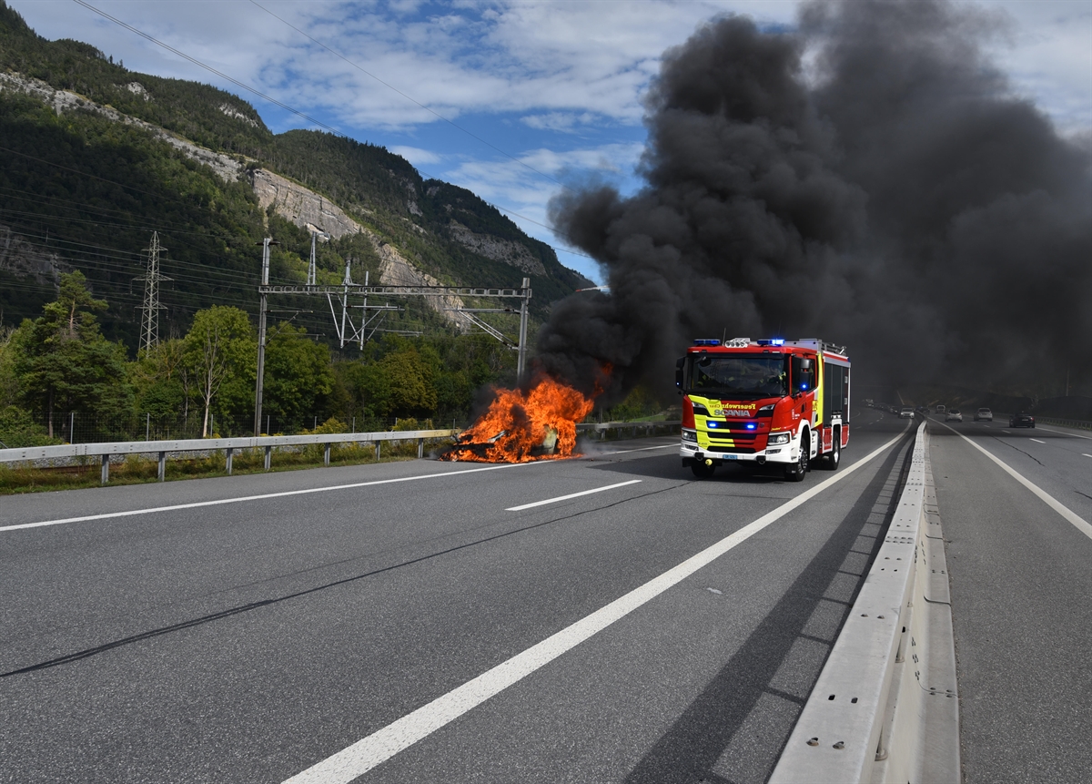 Links der Personenwagen in Vollbrand. Rechts das eintreffende Löschfahrzeug der Feuerwehr.