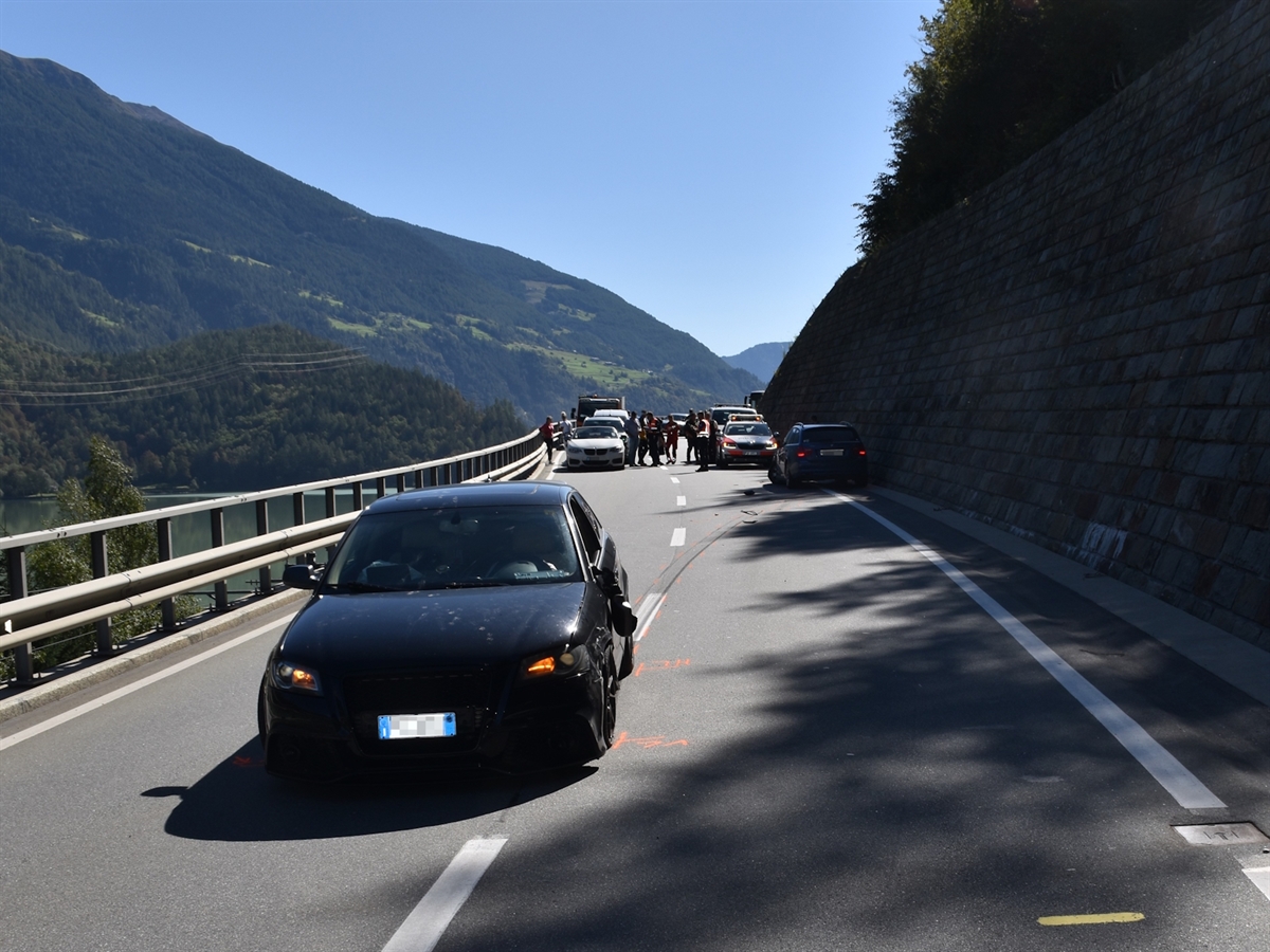 Ein schwarzes Auto von vorne, die linke Seite stark beschädigt. Weiter hinten das zweite Auto mit demselben Schadenbild.