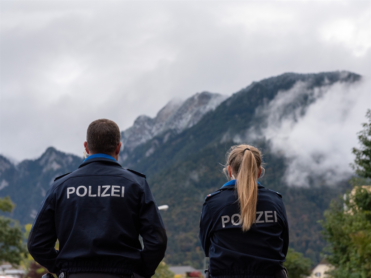Eine Polizistin und ein Polizist beobachten mit dem Rücken zur Kamera, die Umgebung.