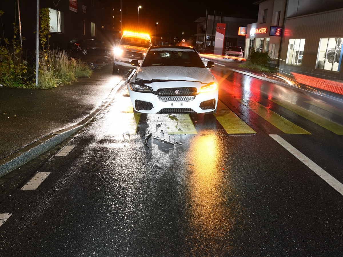 Auf dem Fussgängerstreifen: Das aufgefahrene Auto von vorne. Die Strasse ist nass. 
